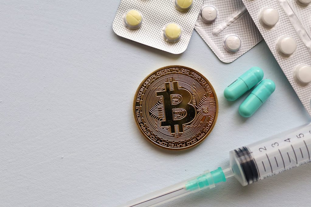 pexels photo 5435971 Image of a Bitcoin coin surrounded by pills and a syringe, symbolizing healthcare and finance.