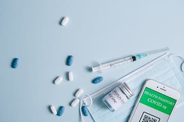 pexels photo 8383879 A flat lay of COVID-19 vaccination items including a mask, syringe, and health passport.